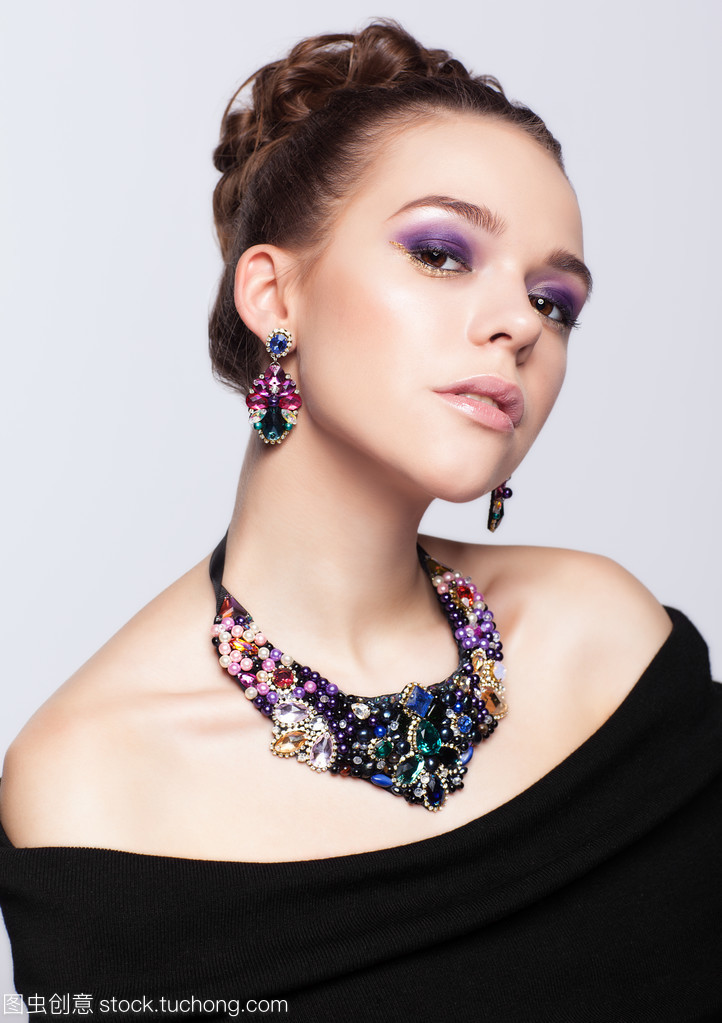 珠宝首饰在灰色的背景上的棕色头发年轻女子